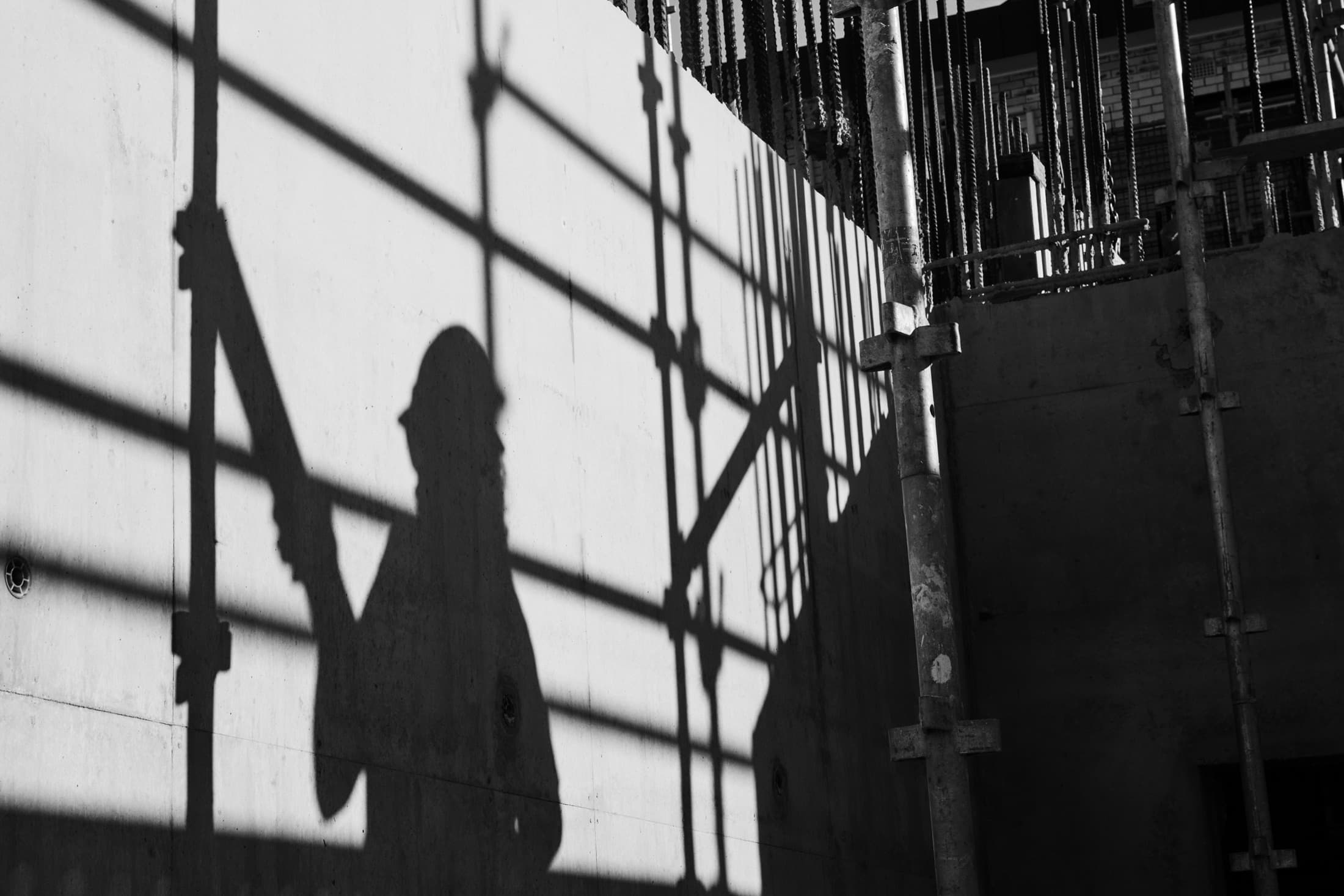 Silhouette of a worker cast on concrete formwork among reinforcement steel on a live construction site