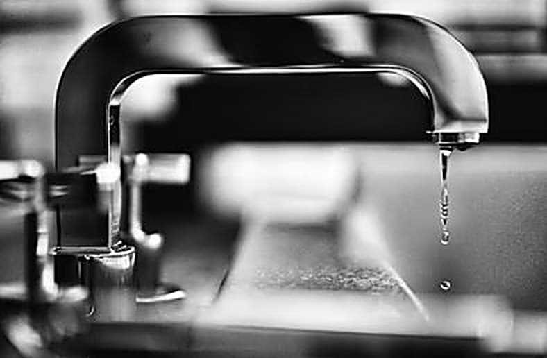 Close-up detail of a commercial tap fitting with a water droplet